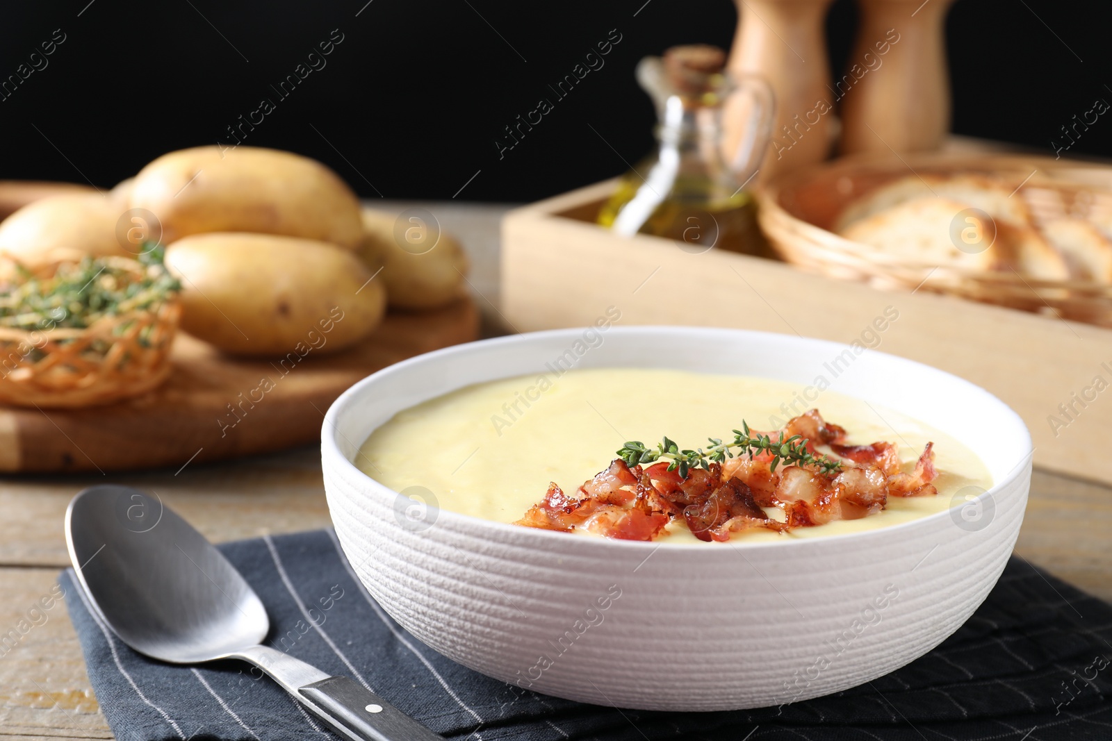 Photo of Tasty potato soup with bacon and rosemary in bowl served on wooden table