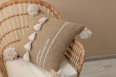 Photo of Stylish soft pillow on armchair near beige wall indoors