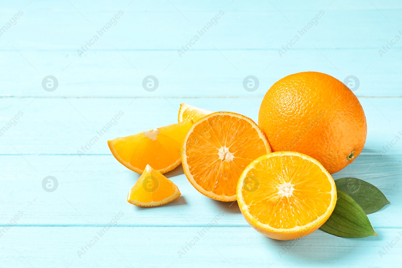 Photo of Fresh oranges with leaves on wooden background, space for text