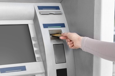 Woman inserting credit card into grey cash machine, closeup
