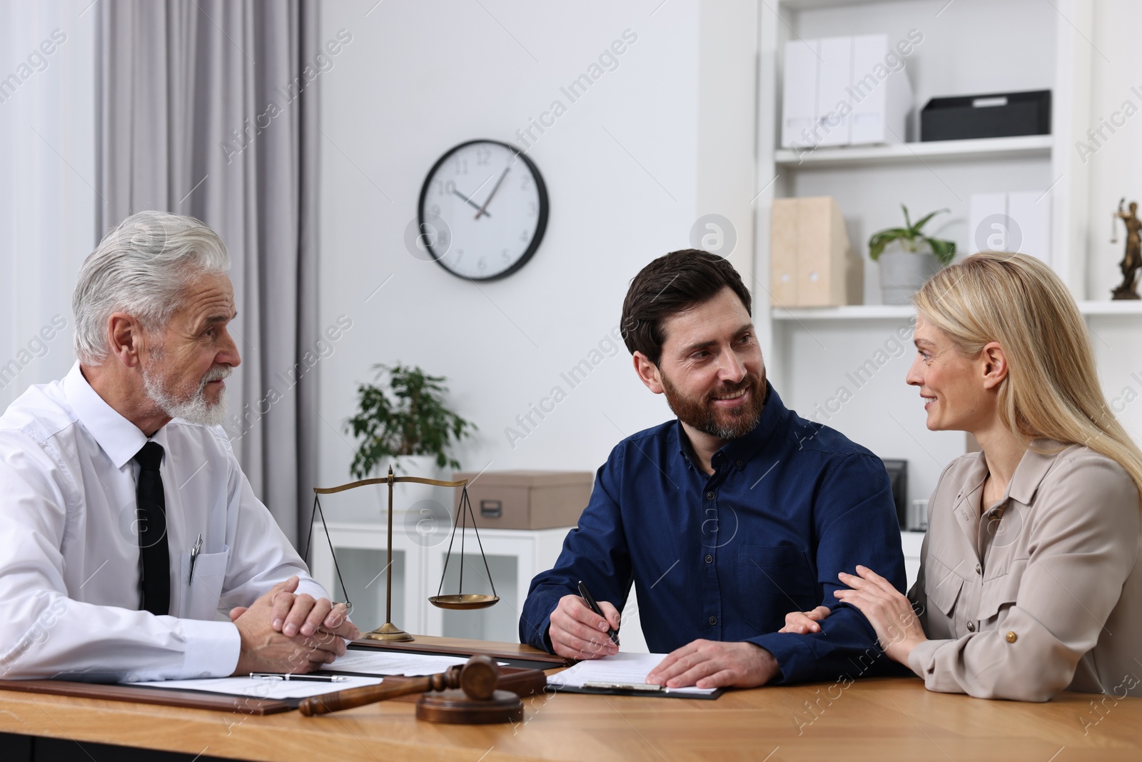 Photo of Happy couple signing document in lawyer's office