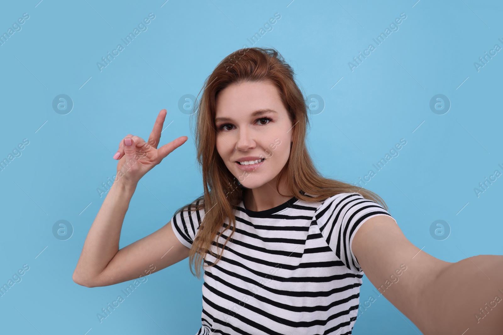 Photo of Beautiful woman taking selfie on light blue background