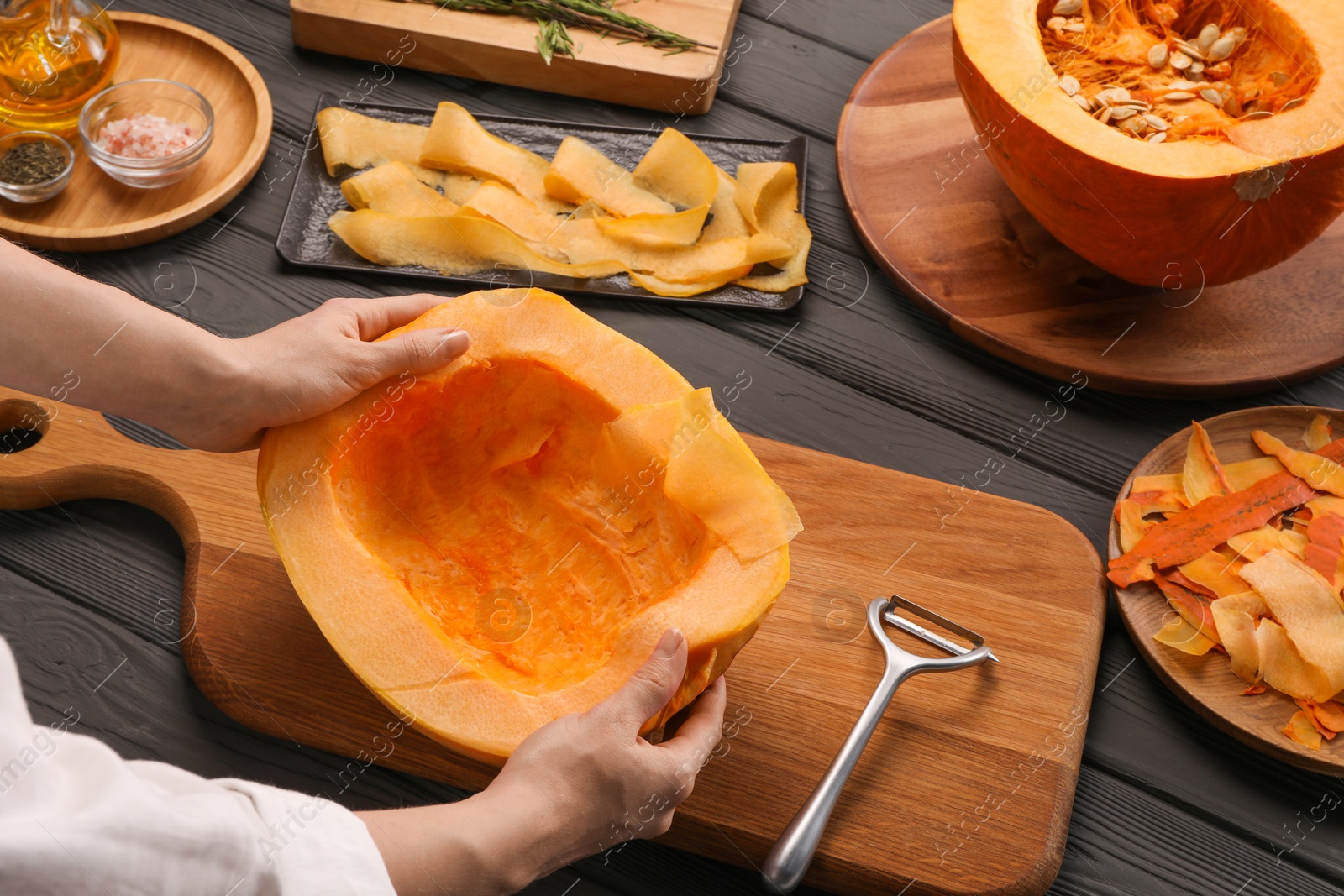 Photo of Woman with half of fresh pumpkin at grey wooden table, closeup