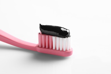 Photo of Brush with charcoal toothpaste on white background