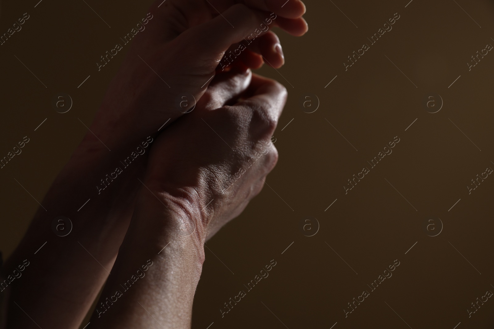 Photo of Woman with ligature marks on her wrists against dark background, closeup. Space for text