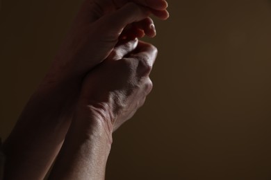 Photo of Woman with ligature marks on her wrists against dark background, closeup. Space for text