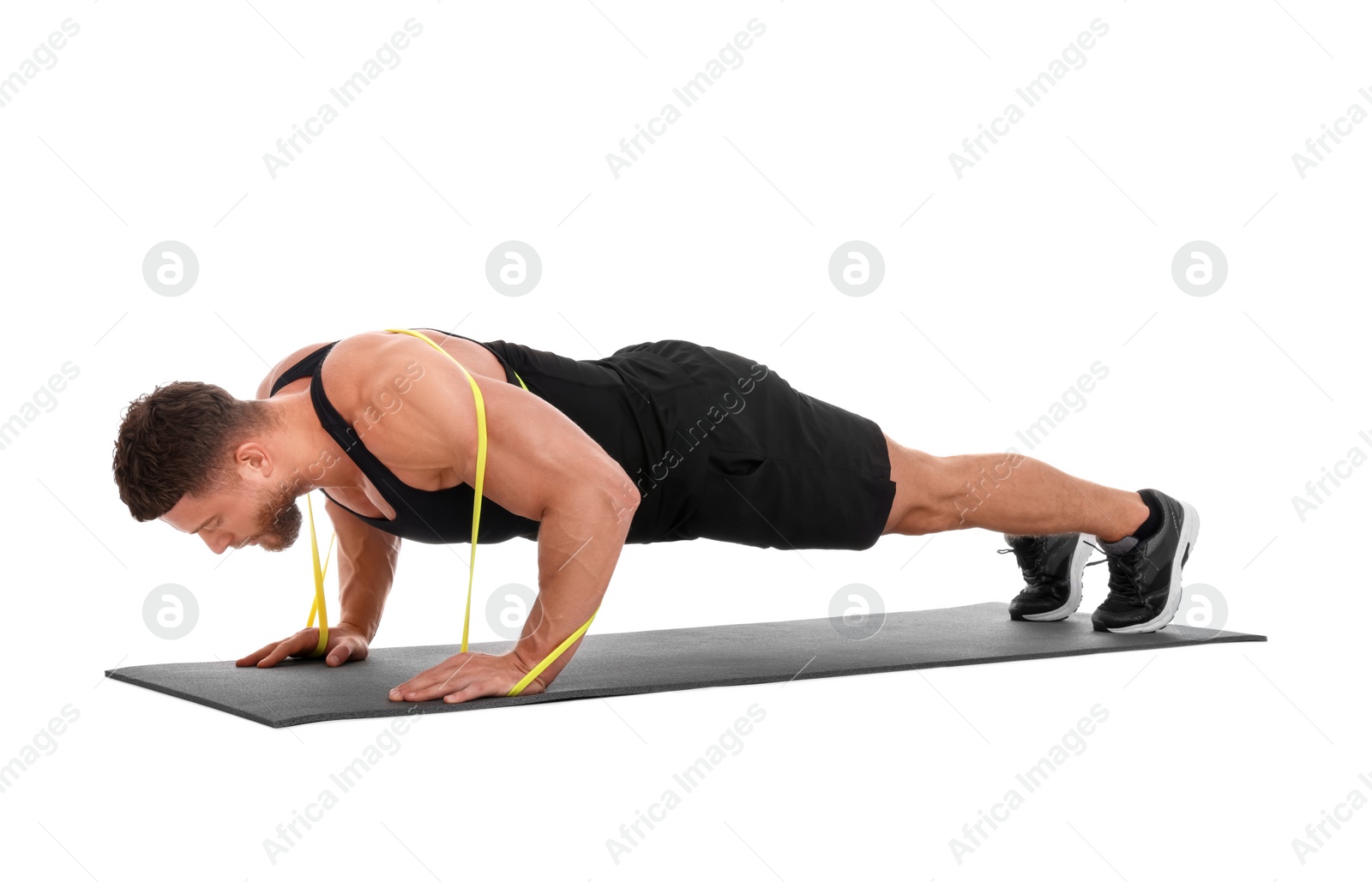 Photo of Young man exercising with elastic resistance band on fitness mat against white background