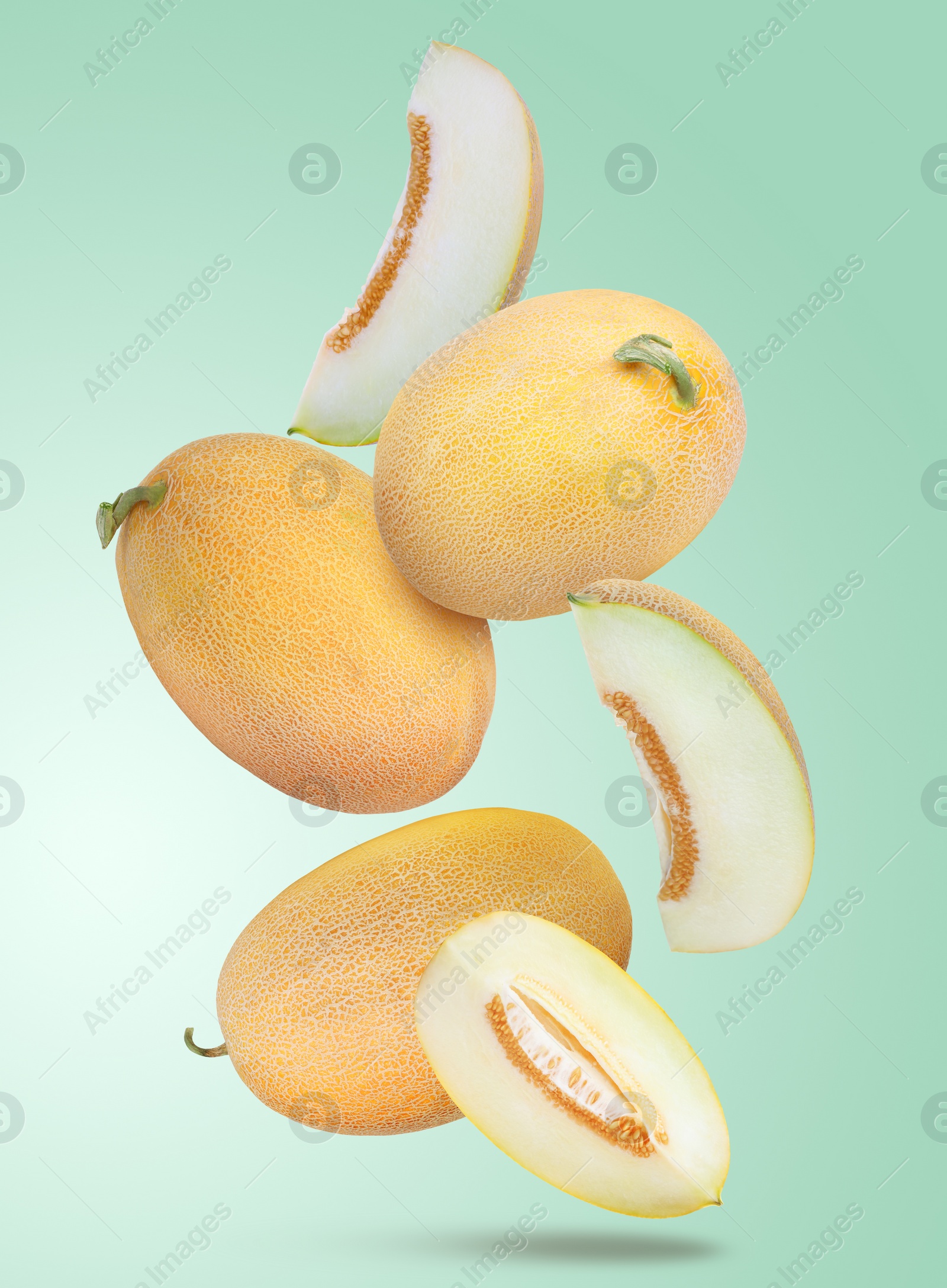 Image of Delicious ripe melons falling on light turquoise background