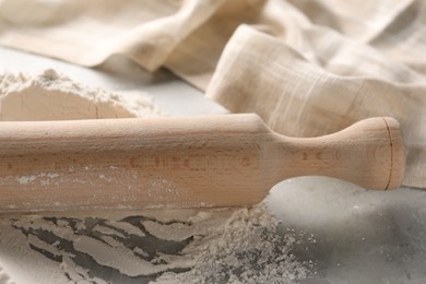 Photo of Pile of flour and rolling pin on grey marble table, closeup