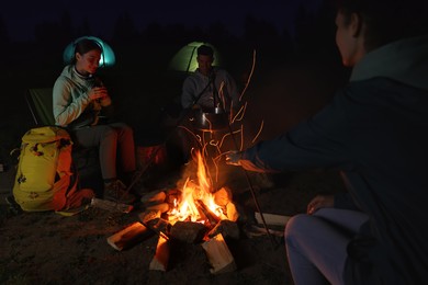 People sitting near bonfire in camp at night