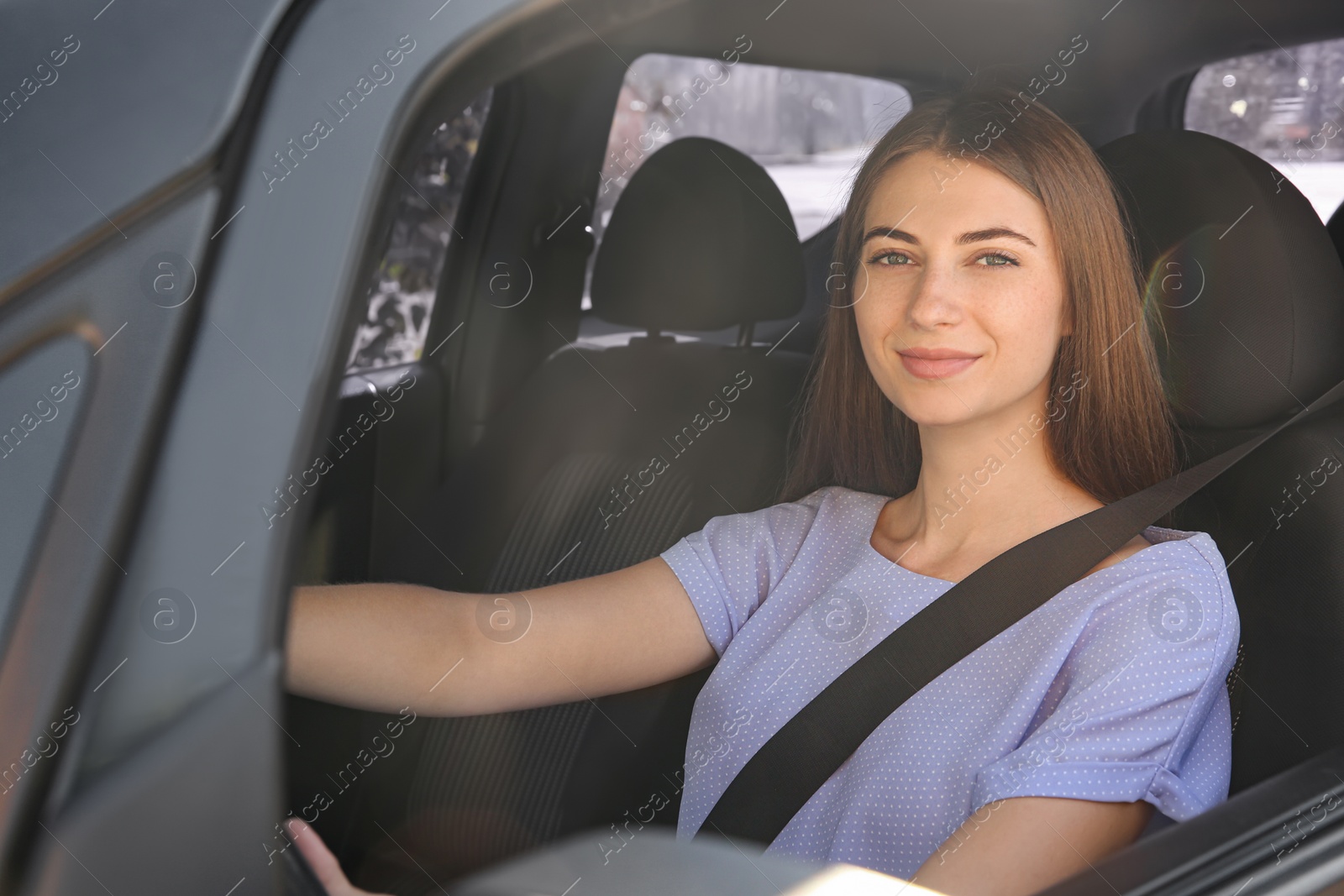 Photo of Young woman with fastened safety belt on driver's seat in car