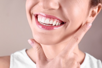 Photo of Young woman with healthy teeth smiling on color background, closeup