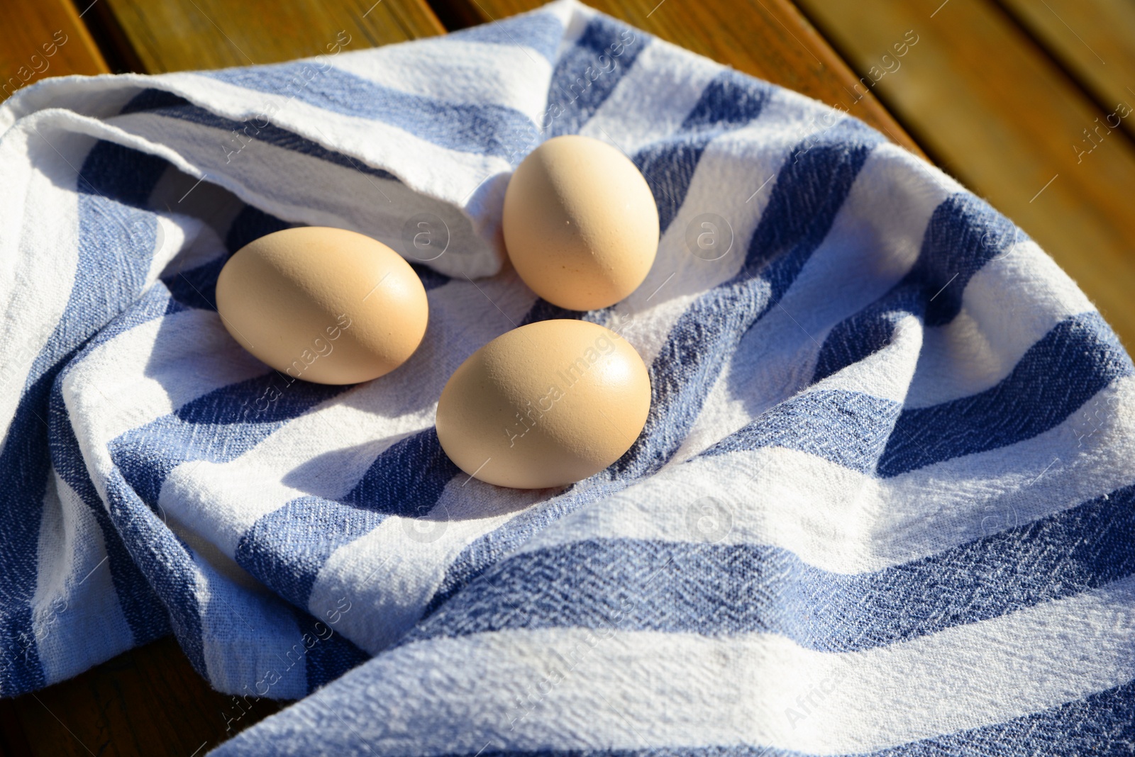 Photo of Raw duck eggs with napkin on wooden table