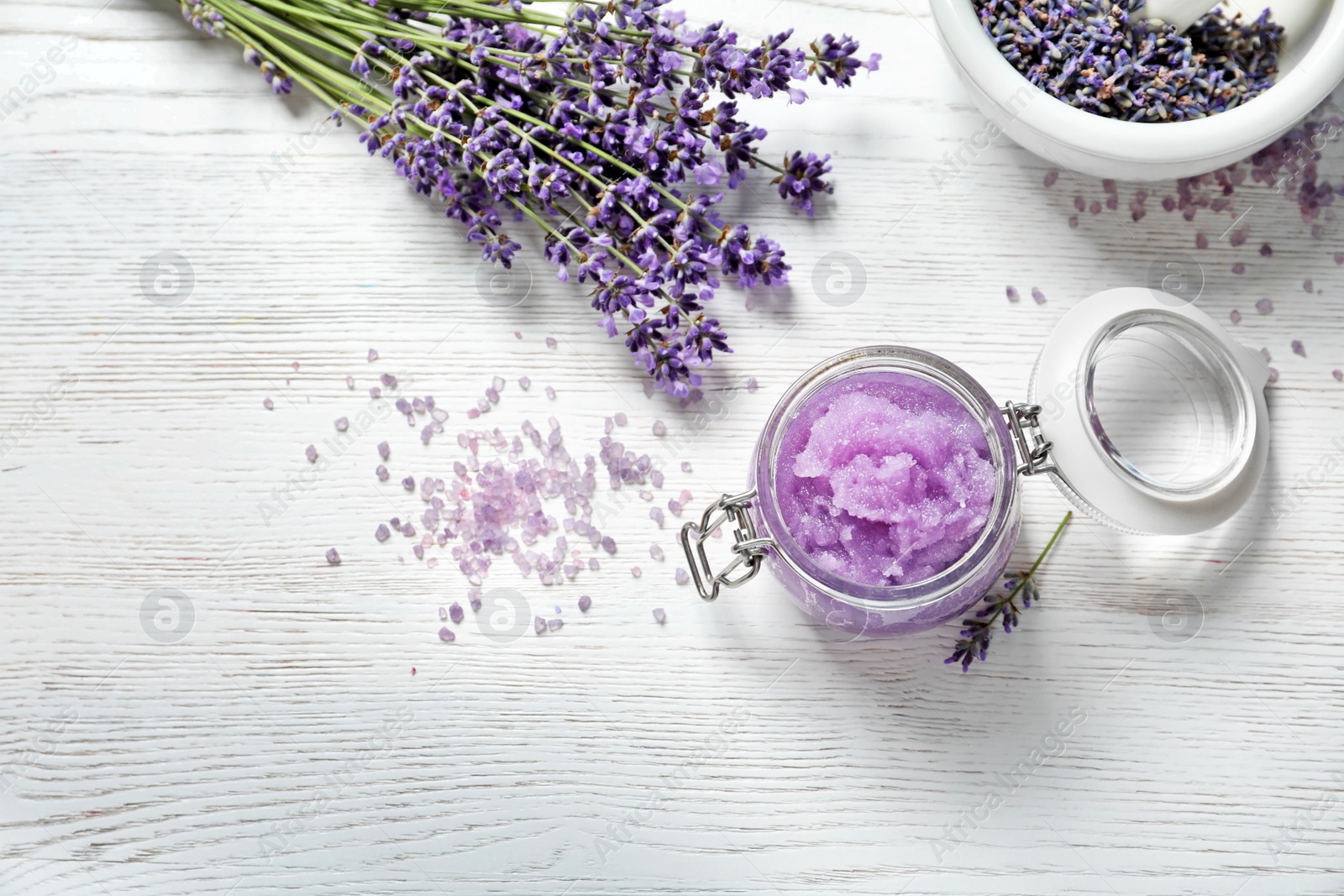 Photo of Flat lay composition with natural sugar scrub and lavender flowers on white wooden table, space for text. Cosmetic product