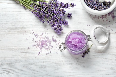 Flat lay composition with natural sugar scrub and lavender flowers on white wooden table, space for text. Cosmetic product