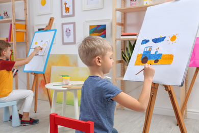 Cute little child painting during lesson in room