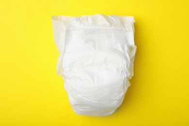 Photo of Baby diaper on yellow background, top view