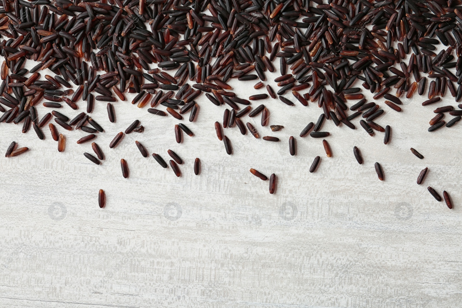 Photo of Black rice on white wooden background. Top view with space for text