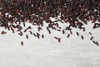 Black rice on white wooden background. Top view with space for text