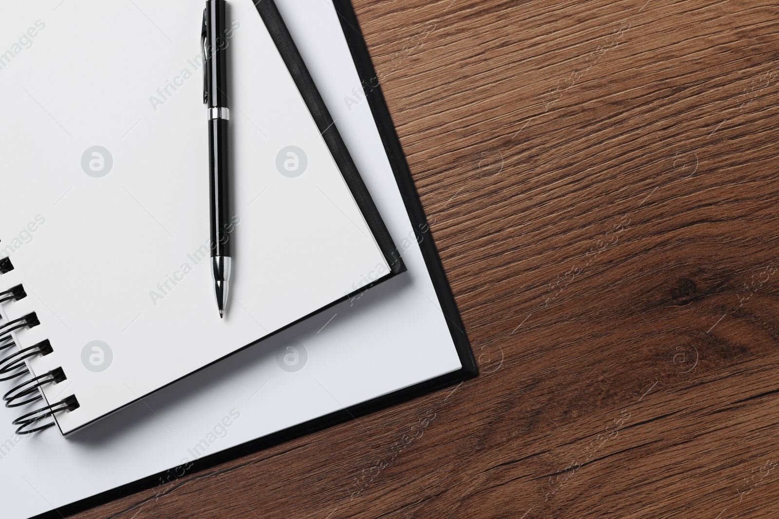 Photo of Ballpoint pen, notebook and clipboard with paper sheet on wooden table, flat lay. Space for text