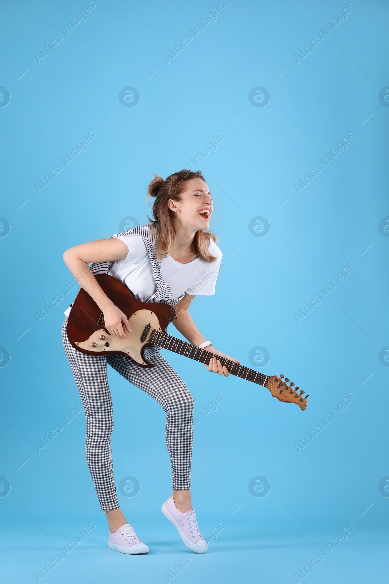 Photo of Young woman playing electric guitar on color background