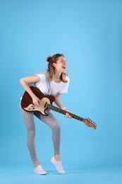 Photo of Young woman playing electric guitar on color background