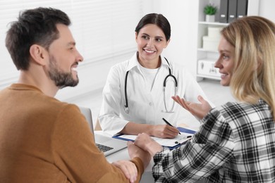Photo of Couple having appointment with fertility doctor in clinic. Patient consultation