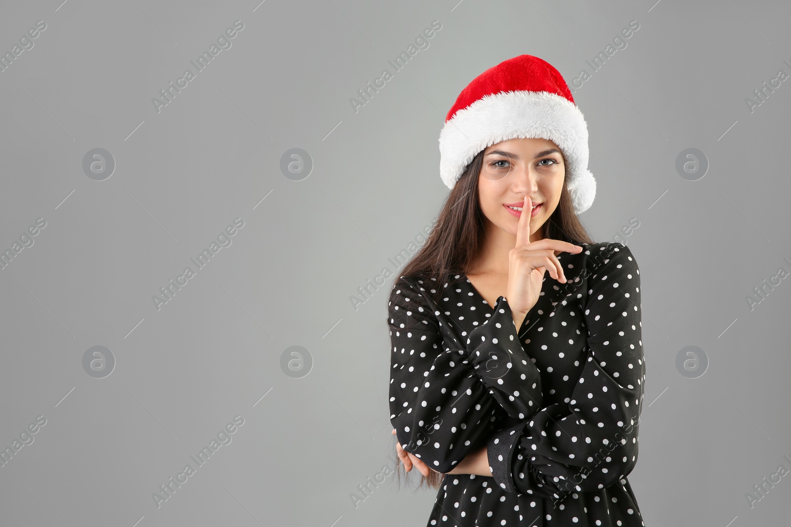 Photo of Young beautiful woman in Santa hat on grey background. Christmas celebration