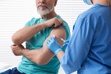 Doctor giving hepatitis vaccine to patient in clinic, closeup