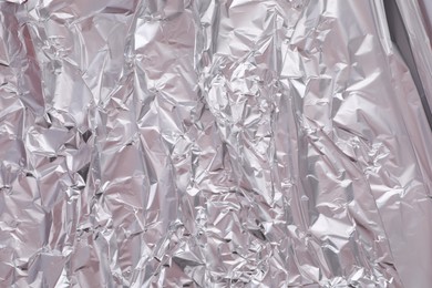 Photo of One sheet of crumpled aluminum foil as background, closeup