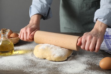 Woman rolling raw dough at table, closeup