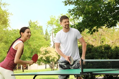 Photo of Happy couple playing ping pong in park