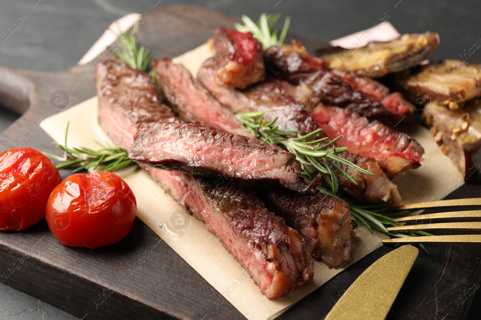 Photo of Delicious grilled beef with tomatoes and rosemary served on table, closeup