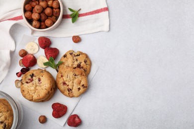 Photo of Cookies with freeze dried fruits, nuts and mint on white table, flat lay. Space for text