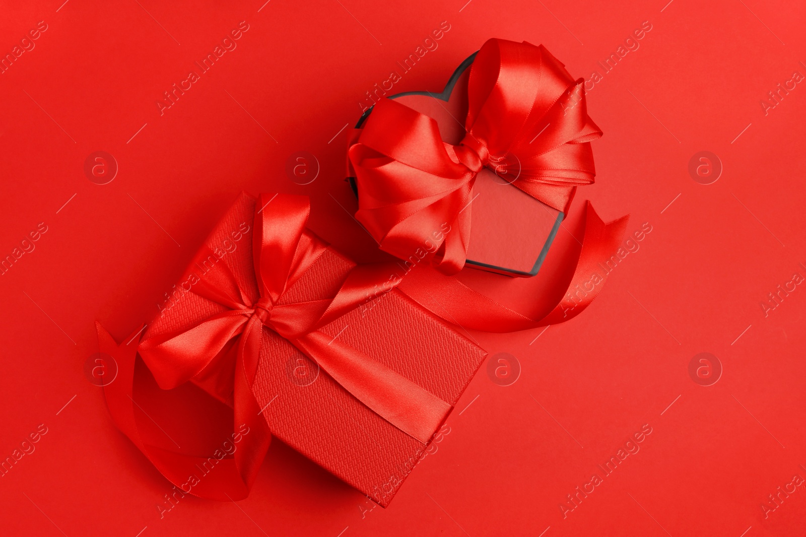 Photo of Beautiful gift boxes with bows on red background, flat lay