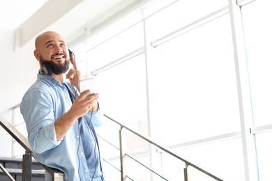 Portrait of young man with mobile phone and headphones on stairs