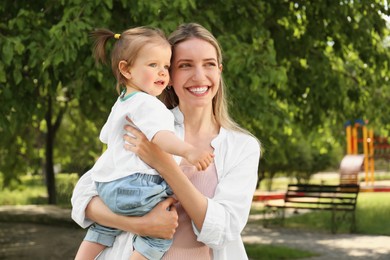 Happy mother with her daughter walking in park. Space for text