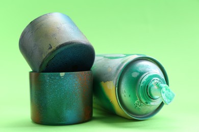Photo of Spray paint can with caps on green background, closeup