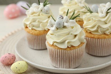 Photo of Tasty Easter cupcakes with vanilla cream and candies on table, closeup