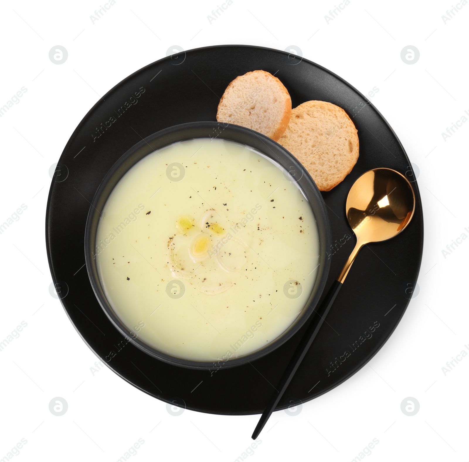 Photo of Bowl of tasty leek soup with bread and spoon isolated on white, top view