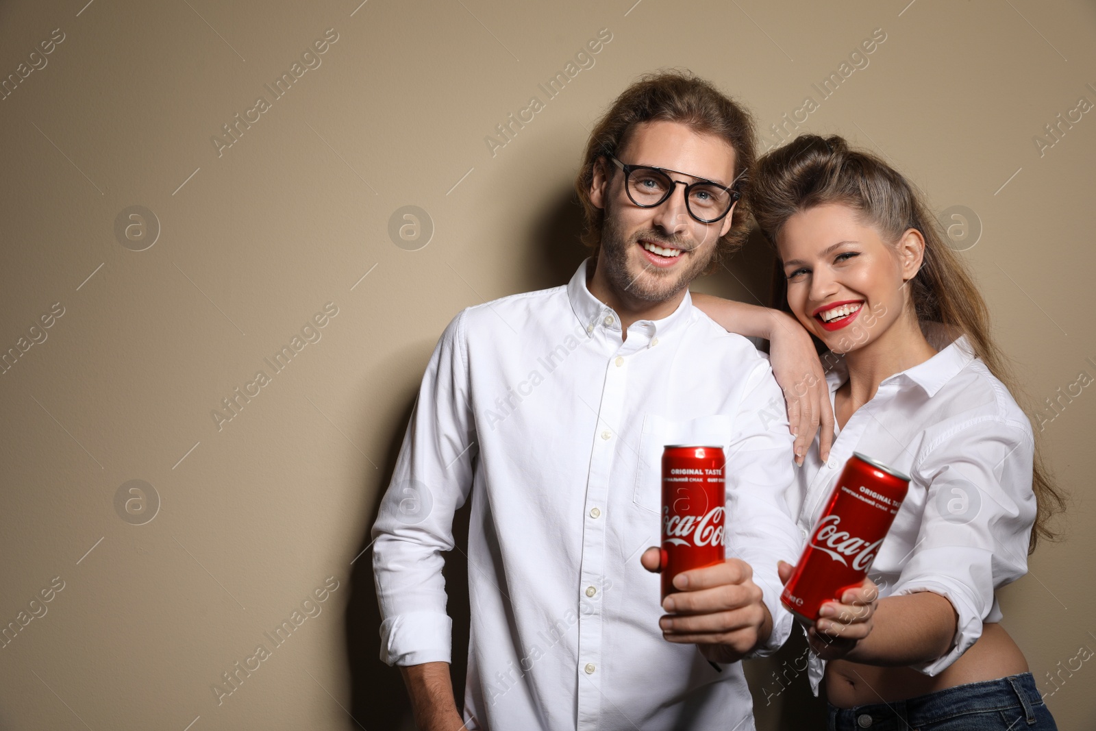 Photo of MYKOLAIV, UKRAINE - NOVEMBER 28, 2018: Young couple with Coca-Cola cans on color background, space for text