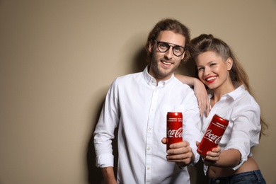 Photo of MYKOLAIV, UKRAINE - NOVEMBER 28, 2018: Young couple with Coca-Cola cans on color background, space for text