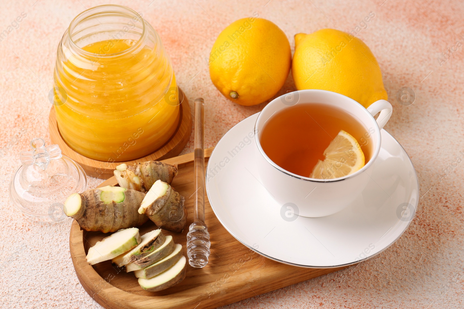 Photo of Tea, honey, lemon and ginger on beige textured table