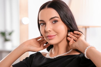 Young woman wearing elegant pearl jewelry indoors