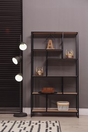 Photo of Stylish shelving unit with decor and lamp near grey wall indoors. Interior design