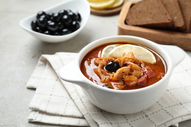 Photo of Meat solyanka soup with sausages, olives and vegetables in bowl on white table, space for text