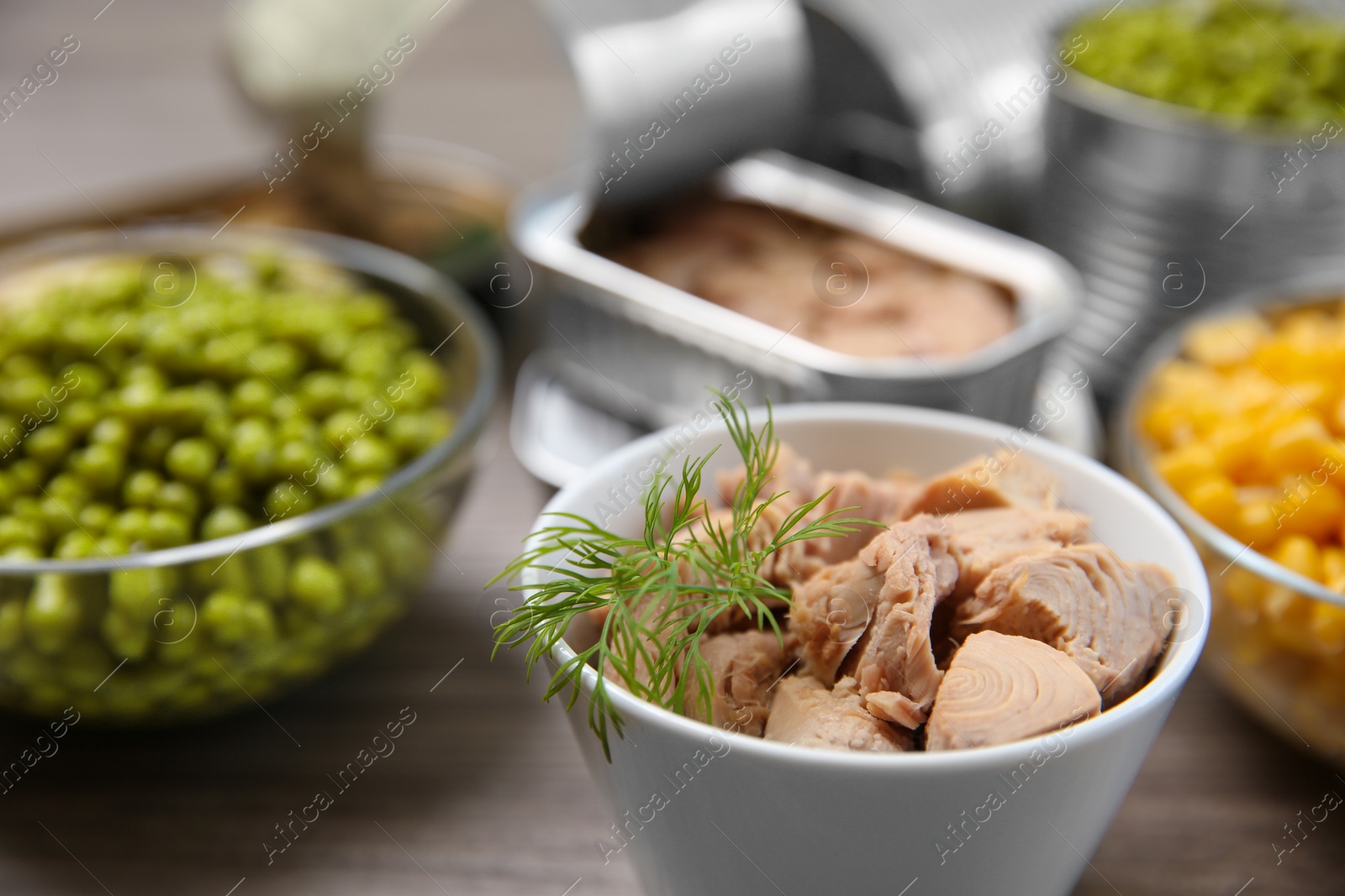 Photo of Bowl of tuna and canned products on table, closeup. Space for text