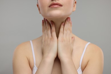 Photo of Woman touching her neck on grey background, closeup