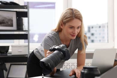 Professional photographer with digital camera at table in office