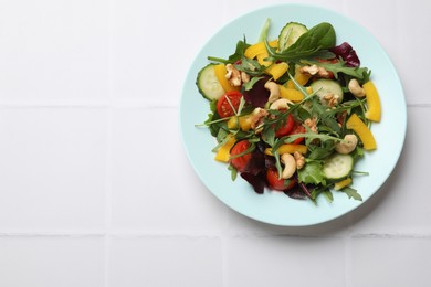 Tasty fresh vegetarian salad on white tiled table, top view. Space for text